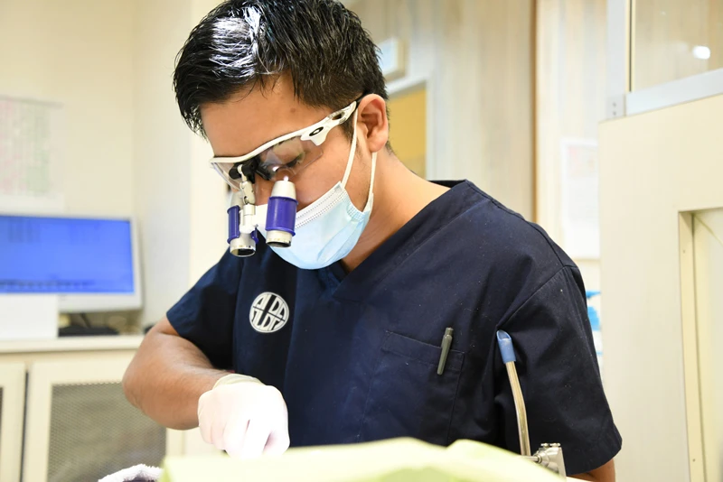 高倍率ルーペで根管治療を行う歯科医師