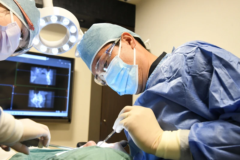 親知らずの抜歯をする歯科医師の写真です／インプラント治療をする歯科医師の写真です