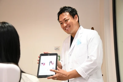 親知らずの抜歯について説明する歯科医師の写真です／審美セラミック治療について説明する歯科医師の写真